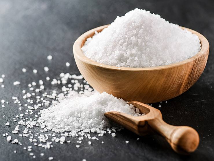 Table salt on a wooden bowl and scoop
